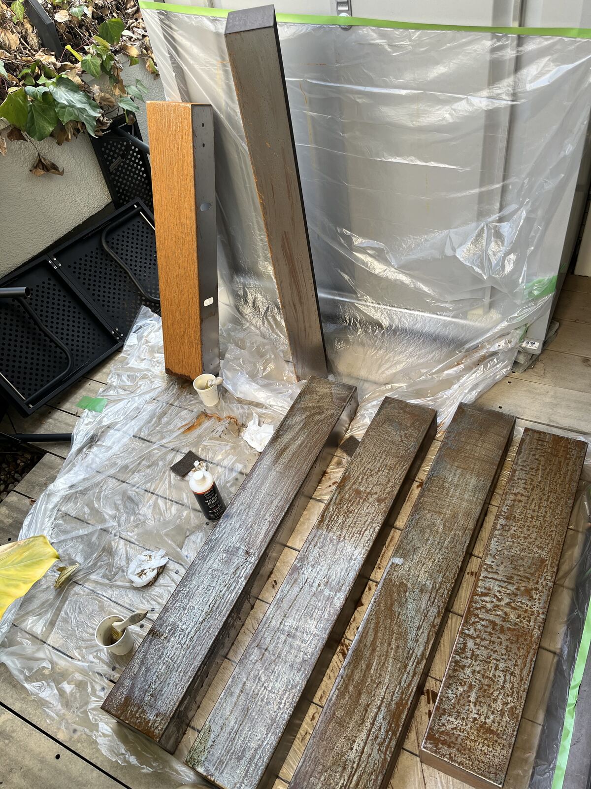シートを敷いた場所に並べた、錆加工中の鉄の外装部材。