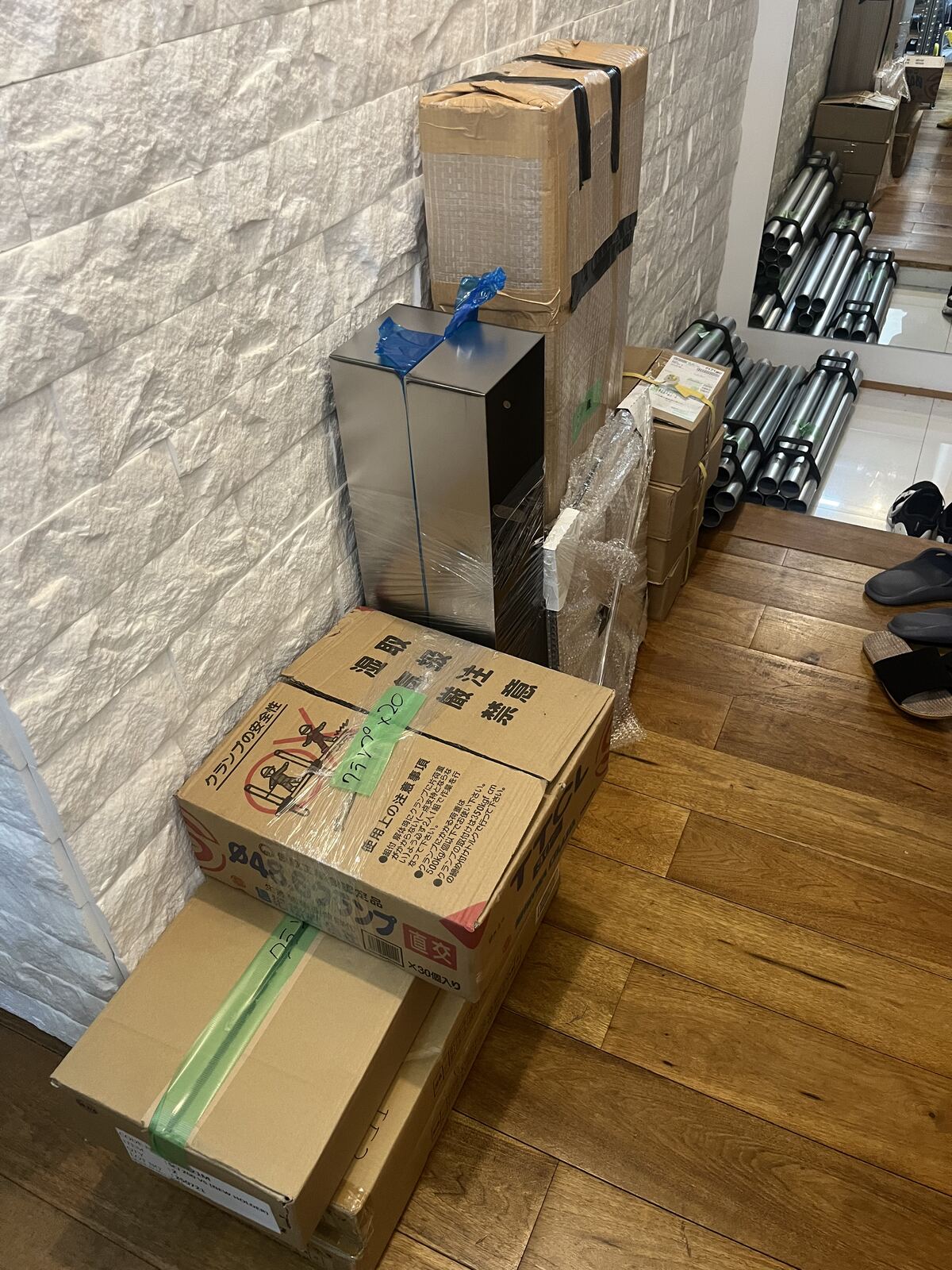箱や緩衝材で梱包した部材と単管パイプ。